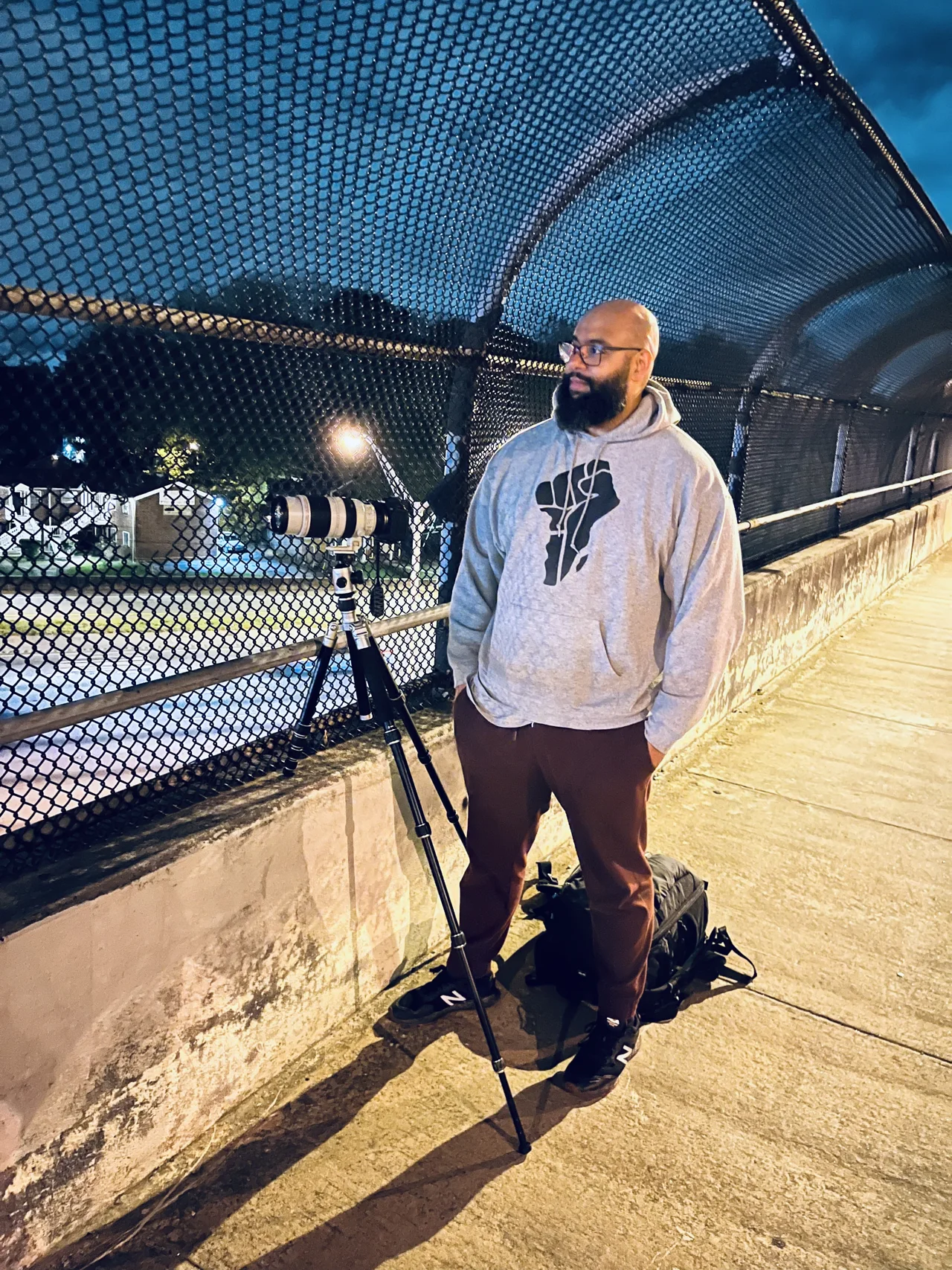 Brandon photographing from a pedestrian bridge at night